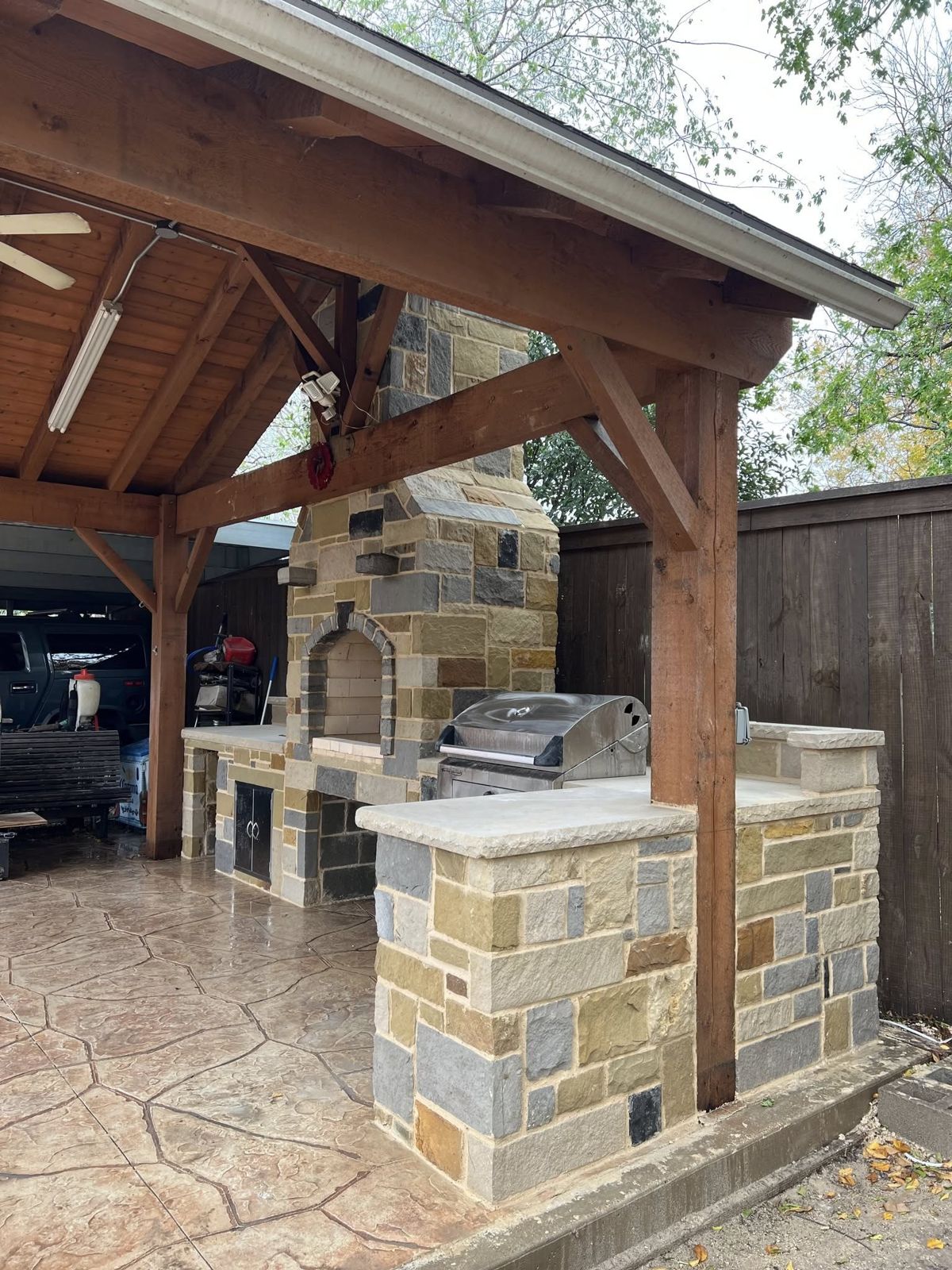 Stone outdoor kitchen under a timber gable cover